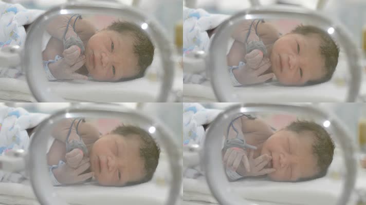 一个可爱的新生儿躺在医院的保温箱上眨着眼