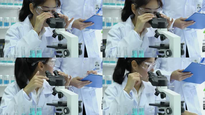 女性看着显微镜与另一位科学家交谈