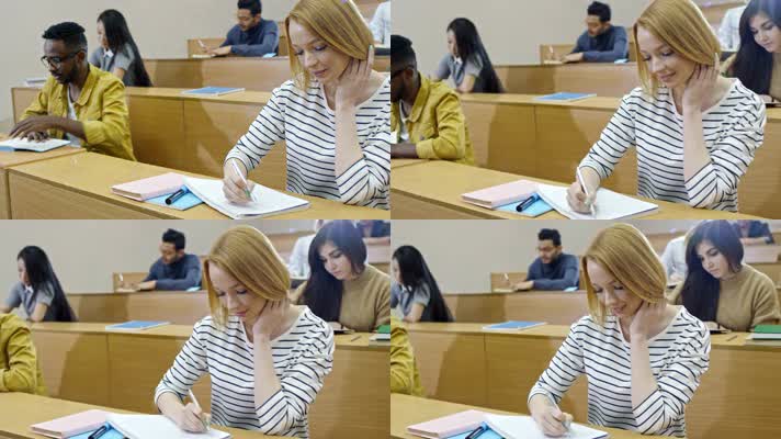 多民族青年学生坐在讲堂课桌前学习